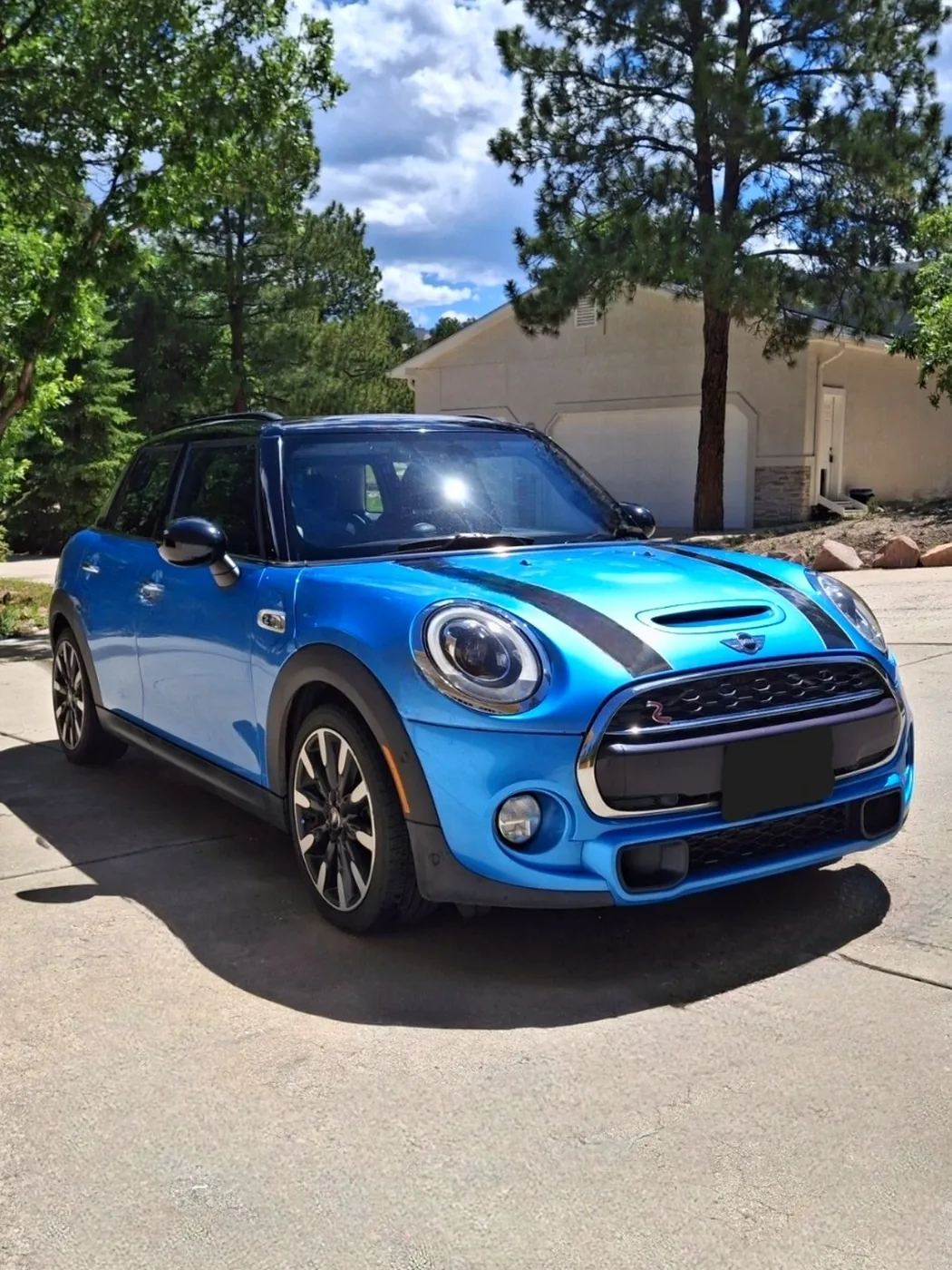 Blue MINI Cooper with a black roof and stripes in a driveway