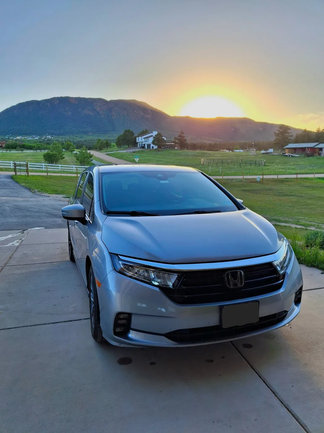 Silver Honda minivan detailed and parked overlooking open fields