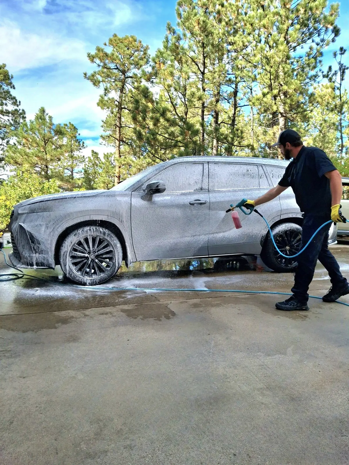 Detailer foaming down an SUV with a foam cannon during a mobile exterior detail in Colorado Springs