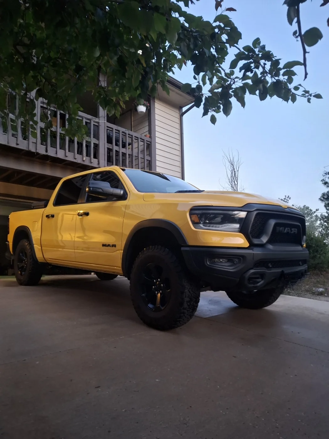 Yellow Ram pickup parked beside a home