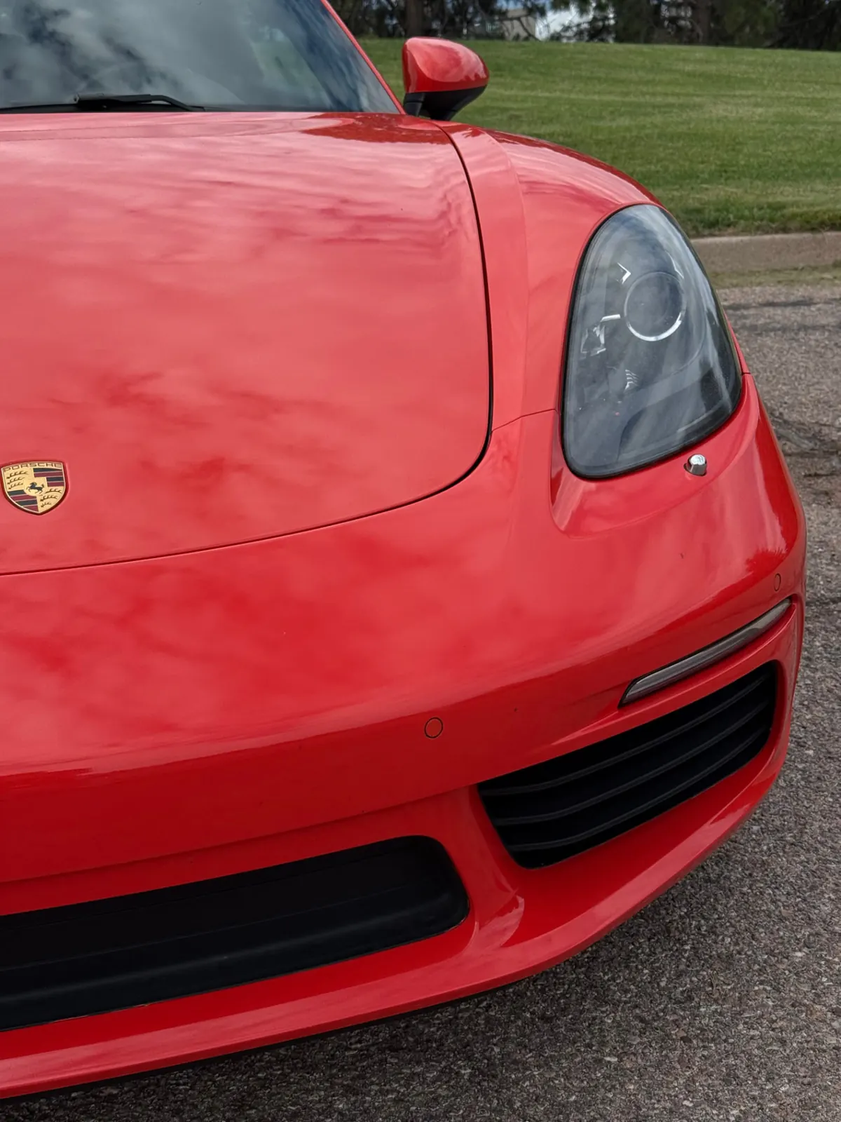 Close-up front end of a red Porsche with the Porsche crest on the hood after a full mobile detail in Colorado Springs